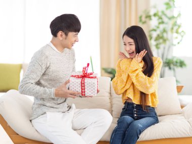 Genç adam kadına oturma odasında bir sürpriz hediye vermek.