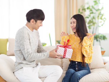 Genç adam kadına oturma odasında bir sürpriz hediye vermek.