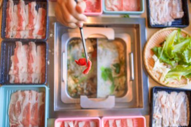 Sıcak tencere yemeği. Elleri yemek çubuklarıyla yemek yiyor..