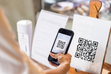 Akıllı telefonu kullanarak QR kodunu tarayan bir kadın..