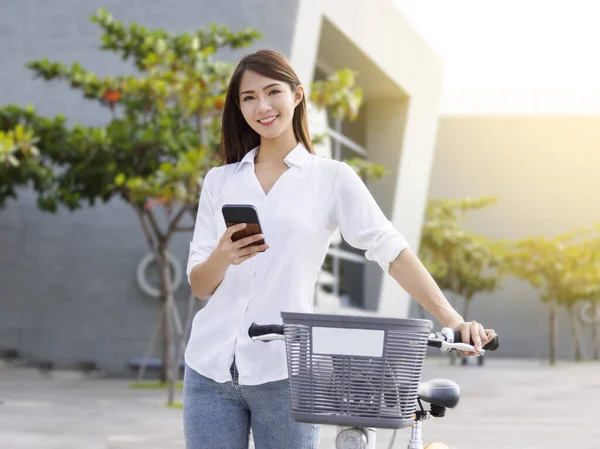 自転車に乗っている間 スマートフォンを使っている若い女性 — ストック写真
