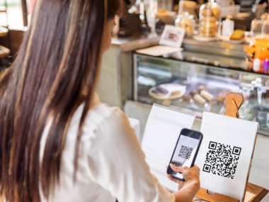 Teknoloji ve Ödeme konsepti. Genç bir kadın akıllı telefonla kablosuz ya da temassız ödeme yapıyor..