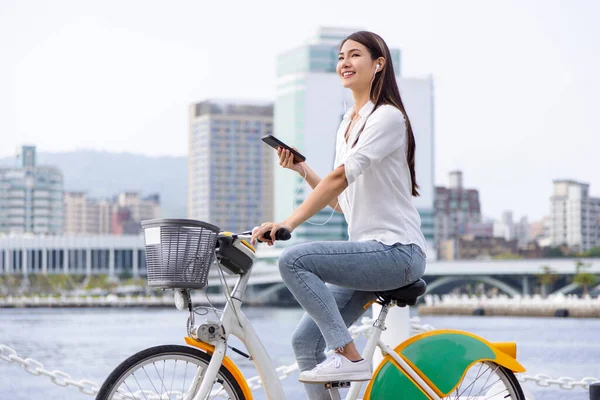 Kulaklıklı Gülümseyen Kız Elinde Akıllı Telefon Parkta Bisiklet Sürüyor — Stok fotoğraf