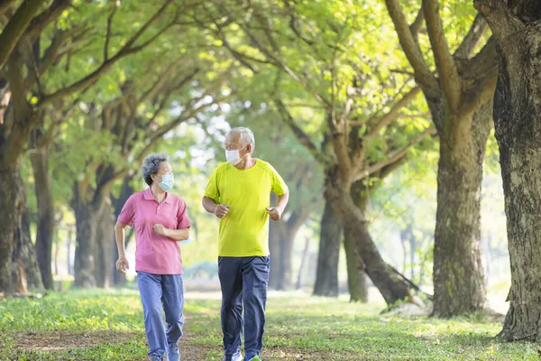 上了年纪的夫妻戴着面具 在公园里慢跑 — 图库照片