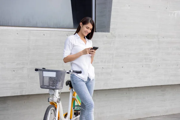 自転車に乗っている間にスマートフォンを使う若い女性 — ストック写真