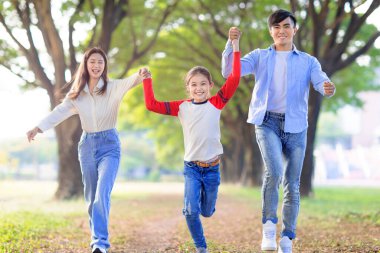 Mutlu bir aile kızı parkta koşuyor ve birlikte oynuyorlar.