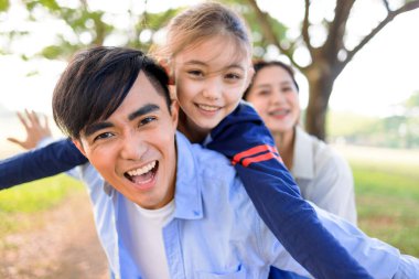 Mutlu bir aile ve kızı parkta oynuyorlar.