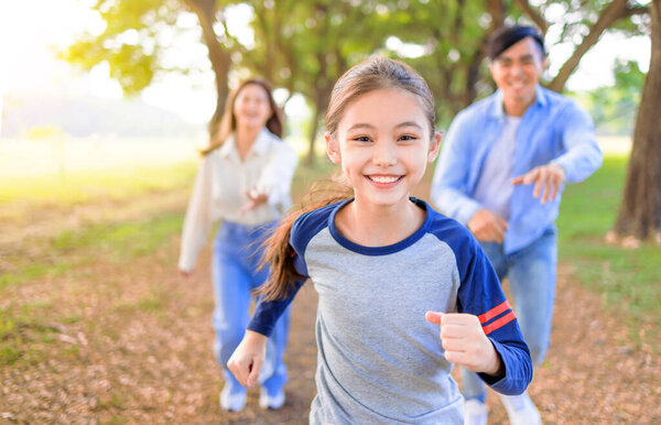 Happy Family with daughter running and playing together in the park