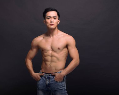 Siyah arka plan üzerinde poz yapan kaslı vücut geliştirmeci adam