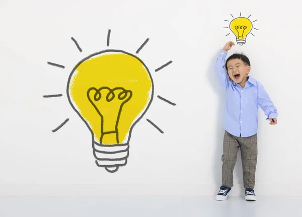 白い壁に子供の学生の思考や電球 かわいい男の子は新しいアイデアを持っています イノベーション技術と教育の概念 — ストック写真