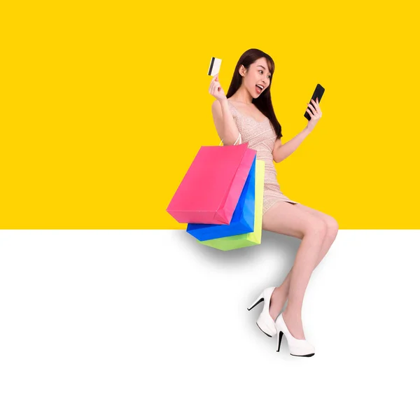 快乐的年轻女子坐在白兰横幅上 使用流动电话概念在网上购物 — 图库照片