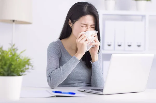 Stressed young  woman sneezing  and working at home office