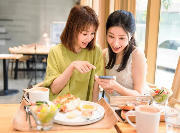 Young Women Sitting Restaurant Looking Mobile Phone Smiling — 스톡 사진