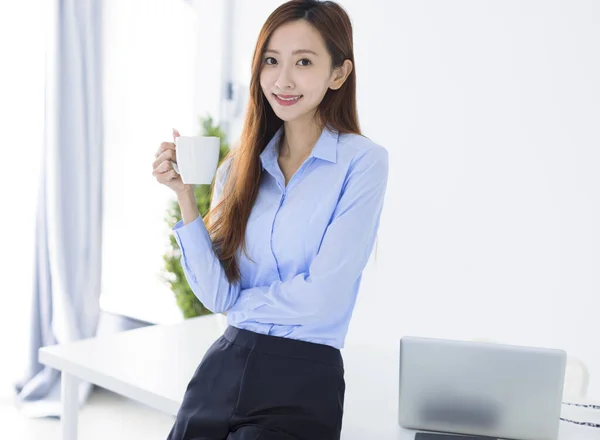 Νεαρή Επιχειρηματίας Χαμογελώντας Και Κρατώντας Κούπα Καφέ Εργασίας Στο Γραφείο — Φωτογραφία Αρχείου