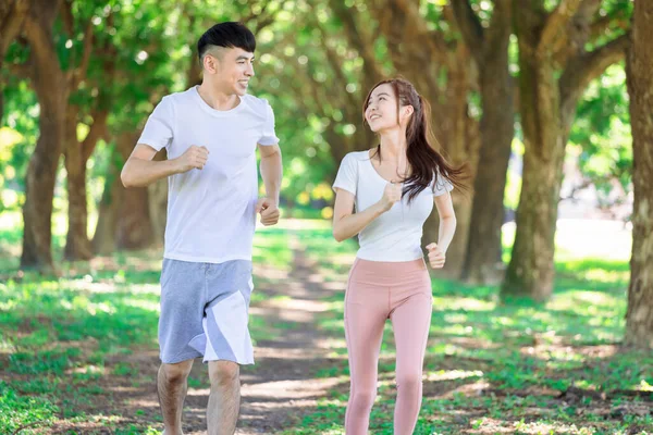 Genç çift güneşli bir günde parkta birlikte koşuyor.