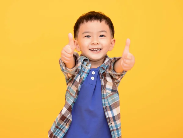 Счастливый Маленький Мальчик Перед Желтым Фоном Показывает Большие Пальцы Вверх — стоковое фото