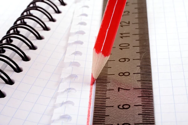 Red pencil draws a flat line with a ruler — Stock Photo, Image