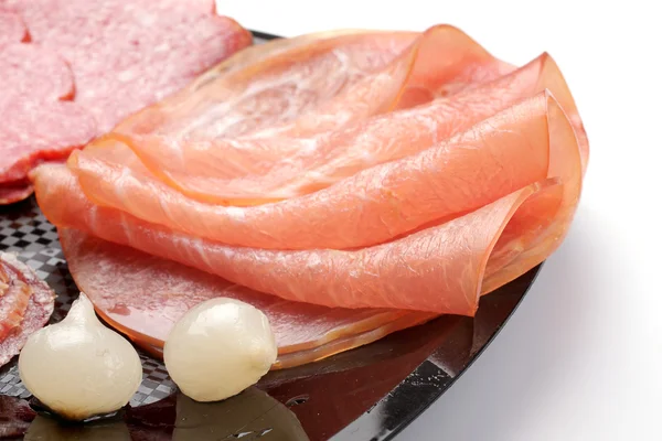 Jamón asado, salami y cebollas pequeñas en un plato negro —  Fotos de Stock