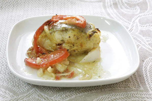 Рыба с помидором и луком на белой тарелке — стоковое фото