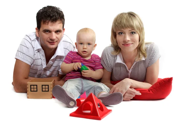 Gelukkige jonge familie liggend op de vloer op rode kussens, witte bac — Stockfoto