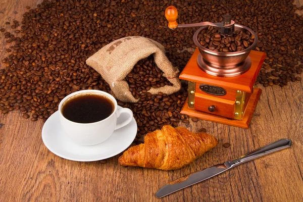 Kaffeetasse mit Croissant und frischen Kaffeebohnen — Stockfoto