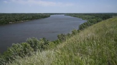 Güzel yaz kırsal doğa manzarası. Mavi nehrin güneşli manzarası ve arka planda ağaçlar olan yeşil çayırlar. Yaz doğasının güzelliği