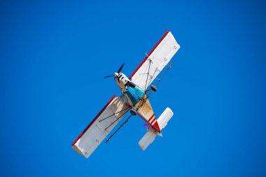 Mavi gökyüzüne karşı küçük bir uçak. Bir tarım havacılık uçağının uçuşu