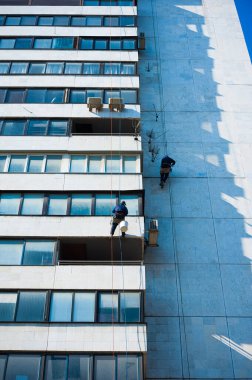 Tırmanışçılar binanın ön cephesinde inşaat ve montaj çalışmaları yapıyorlar.