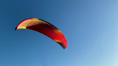 Paraglider mavi akşam gökyüzü ve güzel yaz günbatımının arka planına doğru havalanıyor. Paraşüt.