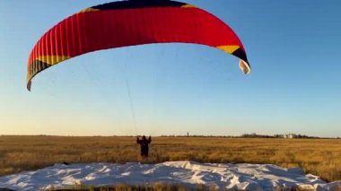 Paraglider mavi akşam gökyüzü ve güzel yaz günbatımının arka planına doğru havalanıyor. Paraşüt.