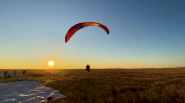 Paraglider mavi akşam gökyüzü ve güzel yaz günbatımının arka planına doğru havalanıyor. Paraşüt.