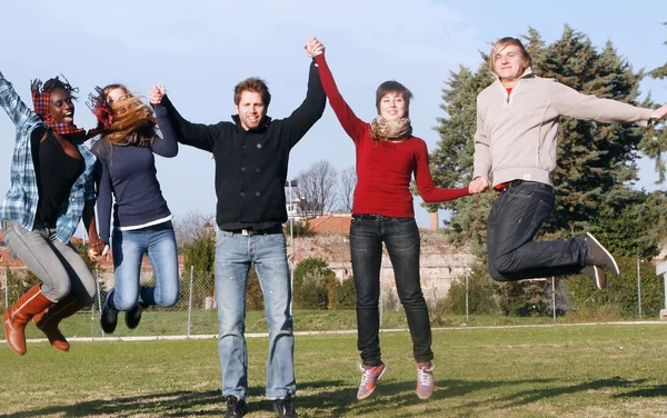 Niños multirraciales saltando felices en el parque Imagen de stock