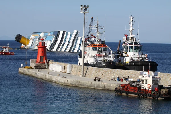 Isola del giglio, Itália - 15 de março de 2013: O navio Concordia frente ao porto de Isola del Giglio de itália.Alguns botes salva-vidas em torno do navio — Fotografia de Stock