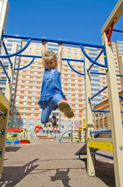 Feliz menina pendura fora travessa no playground — Fotografia de Stock