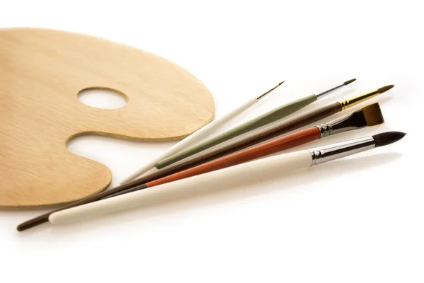 Brushes with wooden palette on white — Stock Photo, Image