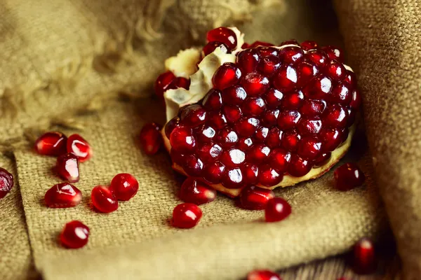 Raw pomegranate with seeds on sacking — Stock Photo, Image