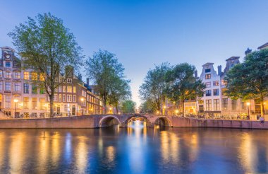 Amsterdam mı? Amsterdam 'ın tarihi şehir merkezinin manzarası. Amsterdam 'ın geleneksel evleri. Güzel bir akşam ve sudaki evlerin huzur dolu yansıması. Bir Avrupa geleneği