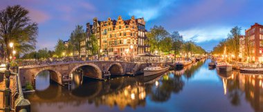 Amsterdam mı? Amsterdam 'ın tarihi şehir merkezinin panoramik manzarası. Amsterdam 'ın geleneksel evleri ve köprüleri. Romantik bir akşam ve sudaki evlerin parlak bir yansıması. Avrupa 'nın tarihi şehrine seyahat. Avrupa, Hollanda, Hollan