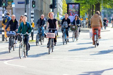 Amsterdam, Hollanda - 24 Eylül 2021: Amsterdam 'da bir caddede bisiklet trafiği. İnsanlar bisiklete biner. Güzel sabah ışığı. Modern bir Avrupa şehrinin şehir hayatı. Amsterdam, Hollanda, Avrupa