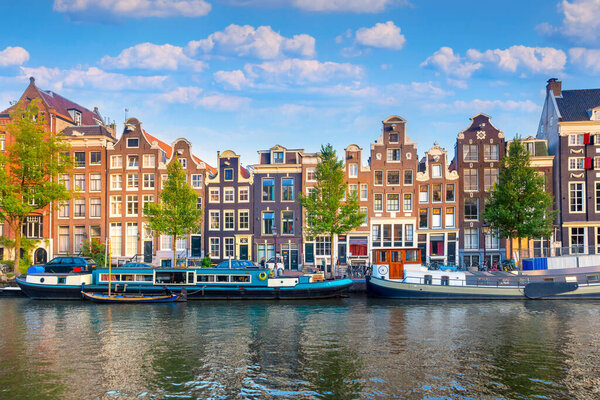 Amsterdam. Panoramic view of the historic city center of Amsterdam. Traditional houses and bridges of Amsterdam. An early quiet morning and the serene reflection of houses in the water. A European journey to a historic town. Europe, Netherlands, Holl