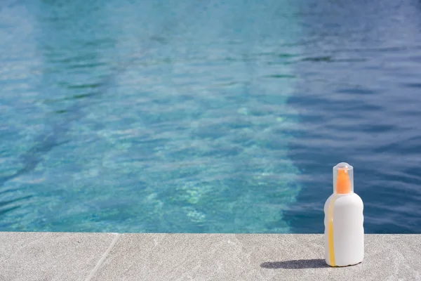 Sun tan lotion poolside — Stock Photo, Image