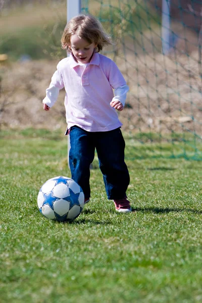 Милый молодой кавказский мальчик играет в футбол или футбол — стоковое фото