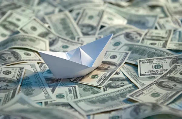 Origami paper boat at sea of money