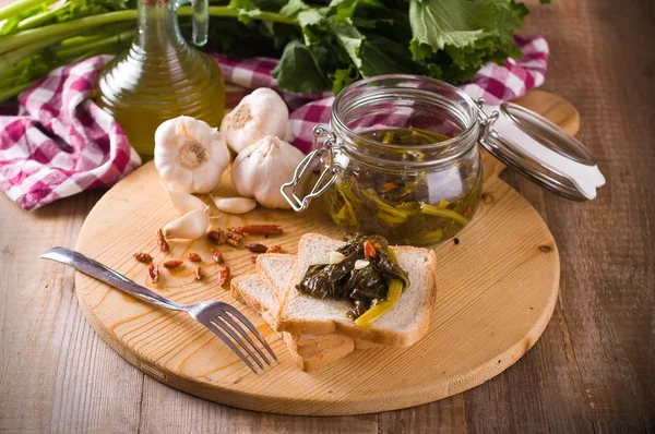 Sliced bread with turnip tops under oil. — Stock Photo, Image