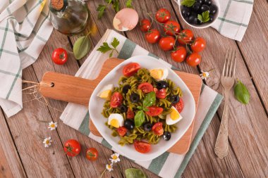Fusilli pasta with cherry tomatoes, eggs and black olives.