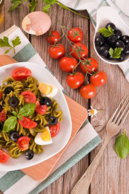 Fusilli pasta with cherry tomatoes, eggs and black olives.