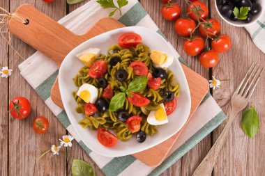 Fusilli pasta with cherry tomatoes, eggs and black olives.