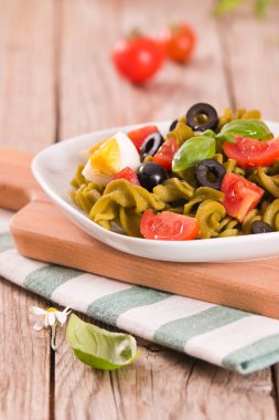Fusilli pasta with cherry tomatoes, eggs and black olives.