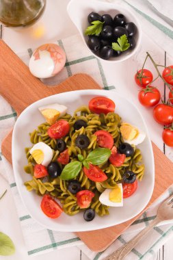 Fusilli pasta with cherry tomatoes, eggs and black olives.