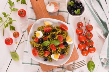Fusilli pasta with cherry tomatoes, eggs and black olives.